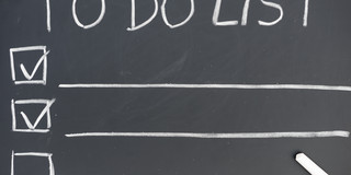 Liste mit Überschrift "To Do List", auf einer Tafel mit Kreide geschrieben.